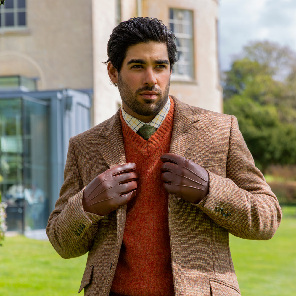 Man wearing brown leather gloves at a country estate