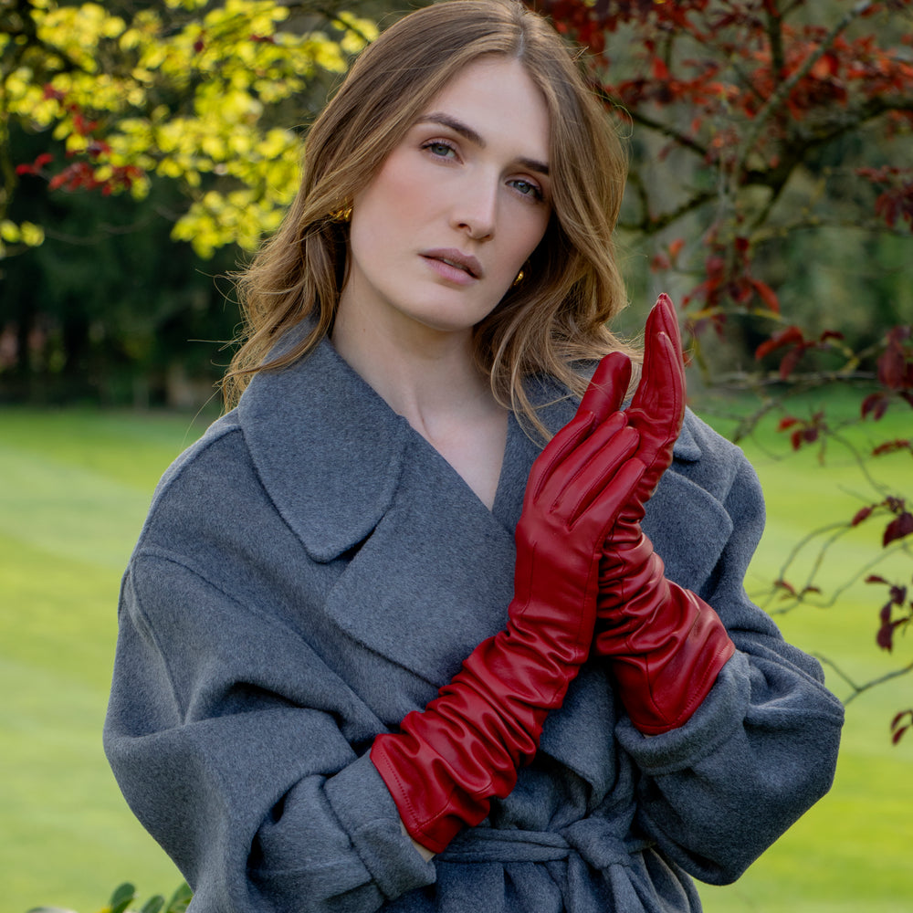 Woman wearing long red leather gloves and coat in the countryside