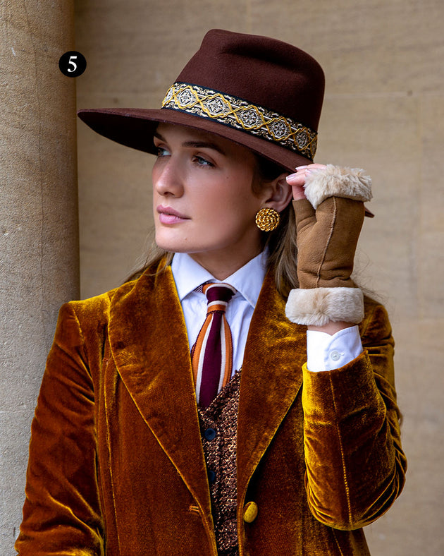 Woman wearing fingerless sheepskin mittens in tan suede