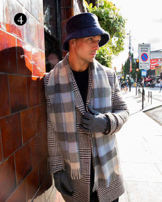 Man wearing cashmere scarf with tweed hat and leather gloves in the city