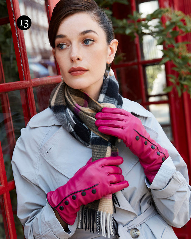 Woman wearing leather gloves with buttons in fuchsia and cashmere scarf outside a red telephone box  