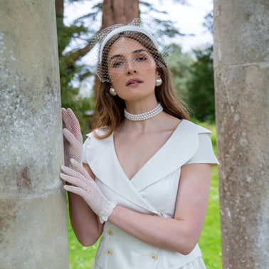 A bride wearing white crochet wedding gloves in the park