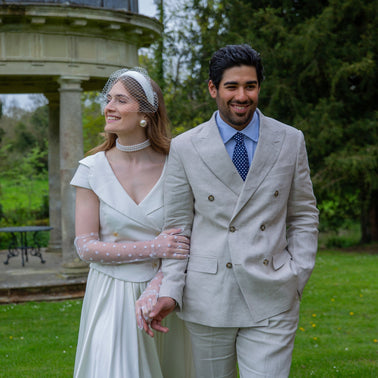 A husband and wife wearing wedding gloves in the park on their wedding day, holding hands