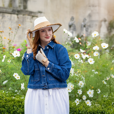 Woma wearing leather and crochet back gloves in white/ivory in the garden. 