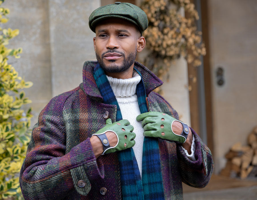 Man wearing leather driving gloves in green outdoors