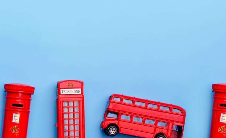 Red toy telephone booth, post box, and bus on a blue background