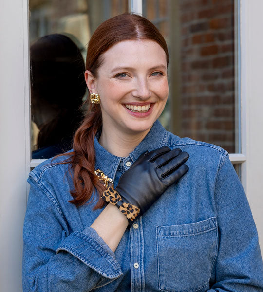 Woman wearing leather gloves in black with animal print bow outdoors