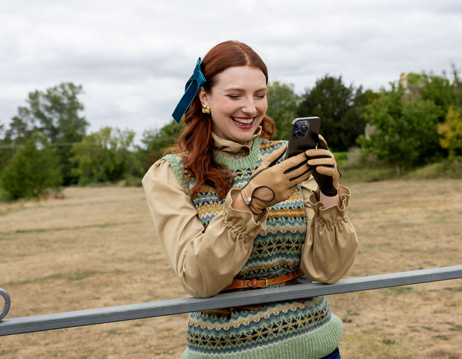 Woman wearing touchscreen leather driving gloves in toffee using her mobile phone outdoors