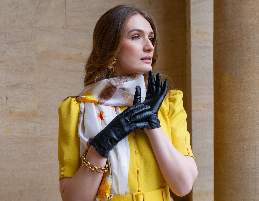 Woman wearing luxury leather gloves in yellow dress and silk scarf. 